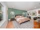 Spacious bedroom with colorful bedspread, green accent wall and hardwood floors at 5218 Addison Dr, Charlotte, NC 28211