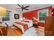 Bedroom with hardwood floors, red accent wall and two windows at 5218 Addison Dr, Charlotte, NC 28211