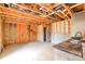 Unfinished living room displaying exposed wooden beams and some partially finished drywall, with a sink area in the corner at 5219 Biederbeck Dr, Charlotte, NC 28212