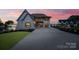 Stunning lakeside two-story home with a long driveway and attached garage, set against a colorful sunset backdrop at 7679 Rabbit Cir, Denver, NC 28037