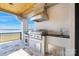 Covered outdoor kitchen featuring a built-in grill, sink, and stainless steel storage with lake views at 7679 Rabbit Cir, Denver, NC 28037
