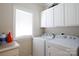 Bright laundry room includes overhead cabinets, large window and washer and dryer at 777 Sanside Dr, York, SC 29745