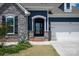 Inviting front entrance with a glass door, stone accents, and well-maintained landscaping at 8000 Millbridge Pkwy, Waxhaw, NC 28173