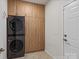 Efficient laundry room with modern stacked washer/dryer, sleek cabinets, and door to exit at 8000 Millbridge Pkwy, Waxhaw, NC 28173