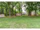 Well-maintained backyard with mature trees, a storage shed, and a glimpse of the house with a screened porch at 8214 Coristar Pl, Huntersville, NC 28078