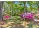 Picturesque backyard featuring colorful azaleas, mature trees, and a glimpse of a fence and a stream at 8214 Coristar Pl, Huntersville, NC 28078