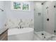 Bright bathroom featuring a soaking tub with marble backsplash and a tiled glass-door shower at 925 Twin Lakes Rd, Rock Hill, SC 29732