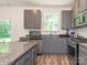 Well-lit kitchen boasts gray cabinetry, stainless steel appliances, granite countertops, and wood-look floors at 11010 Redcoat Hill Ln # 33, Huntersville, NC 28078