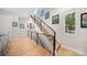 Modern staircase featuring light wood steps, black metal railing, and colorful art adorning the walls at 1115 Greenleaf Ave # B, Charlotte, NC 28202