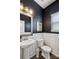Stylish powder room with dark blue walls, white wainscoting, a pedestal sink and wood-framed mirror at 1218 Juddson Dr, Waxhaw, NC 28173