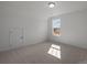 A sunlit bedroom with neutral carpet and white walls is accentuated by a large window showcasing the neighborhood at 124 Canary Ln # 7, Mooresville, NC 28115
