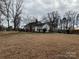 Exterior view of the home and yard showcasing mature trees at 14131 Lucia Riverbend Hwy, Mount Holly, NC 28120