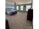 A large carpeted bedroom with multiple windows, a ceiling fan, and a gray upholstered bed at 1905 Yellow Daisy Dr, Matthews, NC 28104