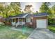 Inviting brick home with an attached garage, covered porch, and a neatly landscaped front yard under sunny skies at 221 Delview Dr, Cherryville, NC 28021