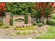 Inviting brick and stone community sign with manicured landscaping and vibrant red flowers at 349 Miners Cove Way, Fort Mill, SC 29708