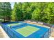 Well-maintained blue and green tennis court in a fenced area surrounded by trees at 349 Miners Cove Way, Fort Mill, SC 29708