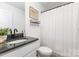 Bathroom featuring granite countertop, framed botanical art, and white shower curtain with textured stripes at 409 Woodcrest Ln, Albemarle, NC 28001
