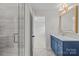 Well-lit bathroom with blue vanity, marble countertop and modern glass shower at 426 Walden Trl, Waxhaw, NC 28173