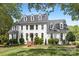Stately white home featuring dormer windows, black door, brick walkway, and manicured lawn at 426 Walden Trl, Waxhaw, NC 28173
