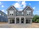 Front view of a gray two-story townhome featuring white columns, covered entryway, and convenient two-car garage at 511 Bowman Rd, Charlotte, NC 28217
