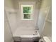 Bathroom featuring a white bathtub with subway tile and a window for natural light at 589 Fork Rd, Norwood, NC 28128