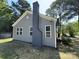 Side view of a gray home featuring a prominent brick chimney and green backyard at 589 Fork Rd, Norwood, NC 28128