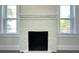 Cozy fireplace with a fresh coat of white paint flanked by two bright windows at 589 Fork Rd, Norwood, NC 28128