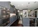 Modern kitchen with gray cabinets, stainless steel appliances, granite countertops, and large island with cowhide stools at 10707 Charmont Pl, Huntersville, NC 28078