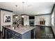 Open living room featuring granite kitchen island, fireplace with mantle, dark trim, and hardwood floors at 10707 Charmont Pl, Huntersville, NC 28078