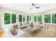 Bright sun room features large windows showcasing views of lush greenery, a ceiling fan, and neutral tones at 11732 Borchetta Dr, Charlotte, NC 28277