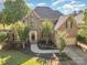 Stunning brick two-story home with well-manicured lawn and mature trees, with a driveway leading to a two-car garage at 12004 Willingdon Rd, Huntersville, NC 28078