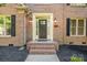 Close-up of brick home's front door framed by elegant trim, lantern sconces and black shutters at 12004 Willingdon Rd, Huntersville, NC 28078