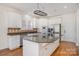 Well-lit kitchen with a large granite island, stainless appliances, white cabinetry, and hardwood floors at 12004 Willingdon Rd, Huntersville, NC 28078