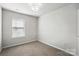 This is a bedroom with neutral carpet and walls, a window with blinds, and light fixture at 14649 Lions Paw St, Charlotte, NC 28273