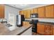 Functional kitchen features a sink, range, microwave, refrigerator, brown cabinets and dark countertop at 14649 Lions Paw St, Charlotte, NC 28273