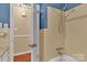 Bathroom featuring shower, tan tile, neutral walls, and wood flooring outside the bathroom at 182 Freedom Mill Rd, Gastonia, NC 28052