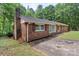 Brick ranch home with red shutters and a brick chimney, surrounded by lush greenery and mature trees at 182 Freedom Mill Rd, Gastonia, NC 28052