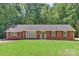 Charming brick ranch home with a lush green lawn and mature trees surrounding the property at 182 Freedom Mill Rd, Gastonia, NC 28052
