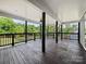 Large covered deck features stained wood flooring, black railing, and a ceiling fan overlooking the wooded backyard at 217 S Green St, Wadesboro, NC 28170