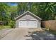 A two-car garage with a basketball hoop and a driveway surrounded by lush greenery at 2224 Clonmel Pl, Charlotte, NC 28262