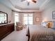 Comfortable main bedroom with a tray ceiling, large windows, and dresser with a mirror at 2306 Wesley Landing Rd, Waxhaw, NC 28173