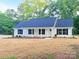 Charming single-story home with a blue roof, white siding, black shutters, and a freshly mulched front yard at 288 Tram Rd, Lancaster, SC 29720
