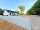 A bright, freshly renovated home with a white exterior and a new concrete driveway, surrounded by natural landscaping at 296 Tram Rd, Lancaster, SC 29720