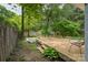 Landscaped backyard with wooden deck, an outdoor dining table set, lush trees, and a storage shed at 4920 Raymond Pl, Charlotte, NC 28205