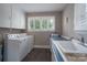 Bright laundry area featuring a washer, dryer, sink, generous countertop, and storage cabinets at 4920 Raymond Pl, Charlotte, NC 28205