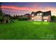 Large backyard featuring a playset, fire pit, patio, screened porch and lush green grass at sunset at 525 Chase Prairie Ln, Waxhaw, NC 28173