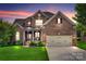 Charming two-story brick home with well-manicured lawn and attached two-car garage at dusk at 525 Chase Prairie Ln, Waxhaw, NC 28173