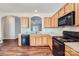 Kitchen featuring wood cabinets, black appliances, and hardwood floors at 5604 Bradford Lake Ln, Charlotte, NC 28269
