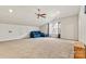 Bright bonus room featuring neutral carpet, a ceiling fan, and a comfortable blue sectional sofa by the window at 5722 Kirkwynd Commons Dr, Charlotte, NC 28278