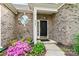 Close-up of a brick house with a front door and flowering bushes at 5722 Kirkwynd Commons Dr, Charlotte, NC 28278